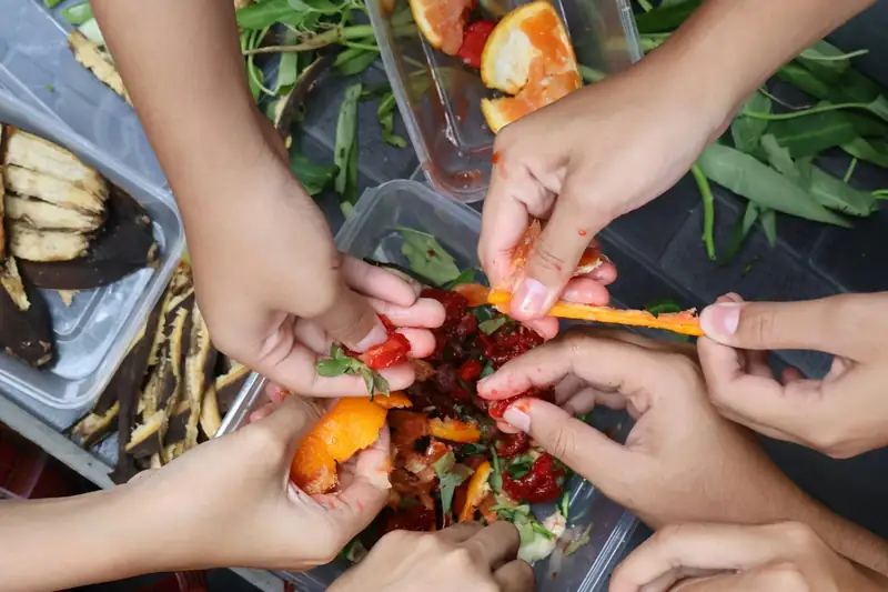 Sorting kitchen scraps into tubs for composting